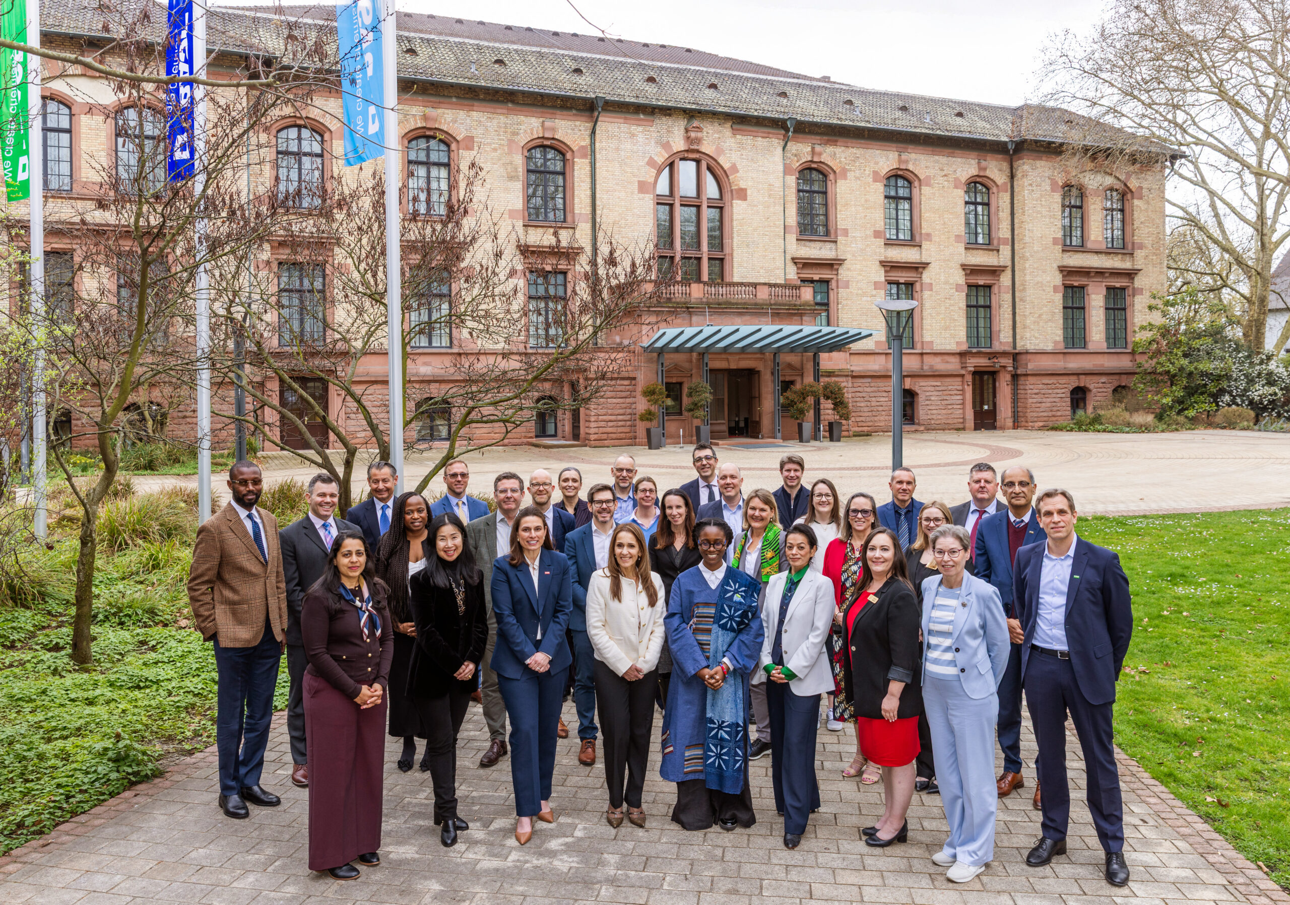 All the attendees to the BASF stand in front of a building and flags ina group photo.